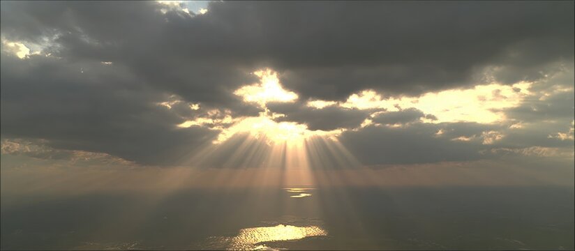 Sunlight breaking through dark clouds over the ocean, creating a dramatic and beautiful scene.