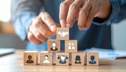 Five wooden blocks form a pyramid on a flat surface, with suited icons below and a handshake icon on top, symbolizing business hierarchy, teamwork, and partnership in a corporate setting.