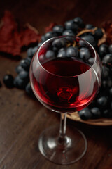 Red wine and blue grapes on an old wooden table.