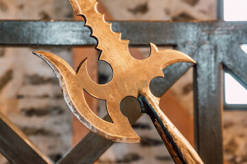 Close up of a golden halberd with sharp blades, evoking fantasy and ancient battles, placed near a...