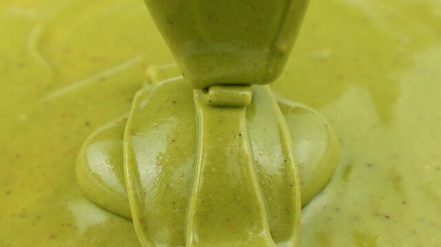Green homemade pistachio paste pouring down close up