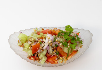 A bowl of salad with cucumber , tomatoes, onions, chillies and sprouts garnished with coriander leaves