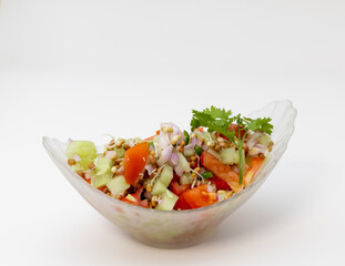 A bowl of salad with cucumber , tomatoes, onions, chillies and sprouts garnished with coriander leaves