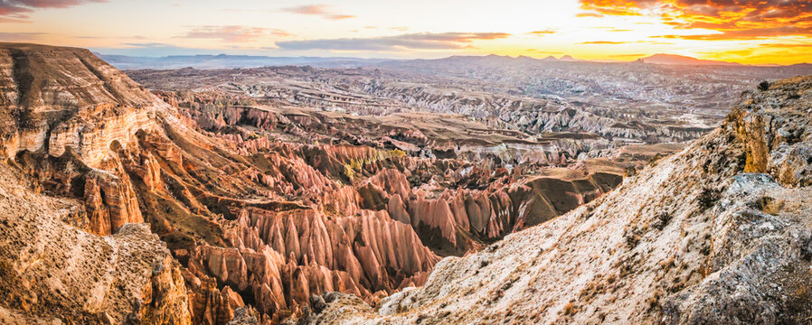 Wide panoramic aerial view of Cappadocia volcanic landscape showing Rose Valley, Red Valley, Zelve and Pasabag Monks Valley at sunset, famous travel destination and UNESCO World Heritage site in Turke