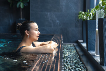 Woman relaxing in spa pool by window. Quiet moment.