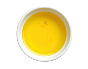 Round white bowl filled with bright yellow liquid, possibly oil or honey, with small air bubbles