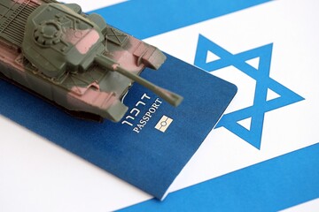 Obraz premium Israel passport and toy tank on flag. The current Israel passport and tank lies on flag close up