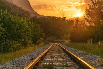 Symmetrical view of railway tracks disappearing into the distance during sunset. Perfect transportation background, travel concept, or inspirational design