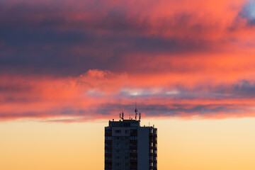 Urban cityscape of a Tallinn residential building with roof antennas against a dramatic, fiery red...