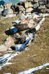 Boulders and snow melt create a natural waterway in a serene landscape during early spring in a mountainous region