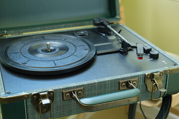 Retro portable record player in a suitcase case with open lid, empty platter, tonearm and controls. Vintage analog audio gear for home music listening or product catalog use