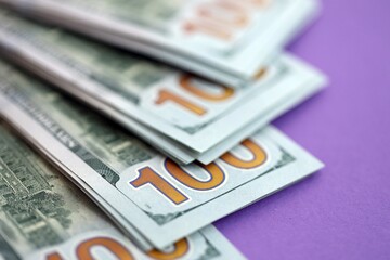 Big amount of United States hundred dollar bills on purple background