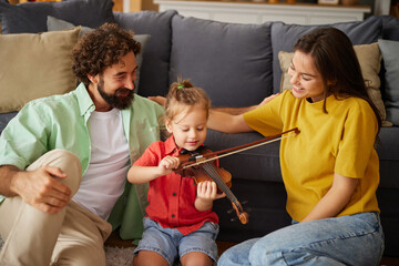 In a warm living room, a smiling child practices violin with dedicated parents nearby, showcasing joyful family time and nurturing moments during a relaxed afternoon.