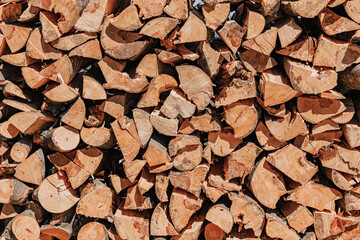 Woodpile showing neatly stacked logs and firewood, ready for burning. Rustic timber background representing renewable energy and sustainability