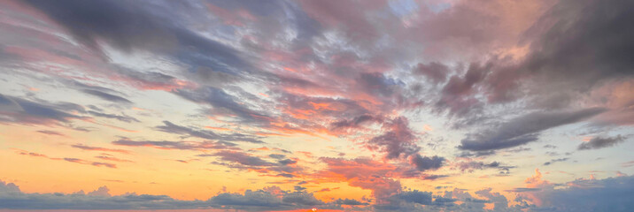 Panoramic landscape with sunset sky, sun light and gold, red and dark clouds