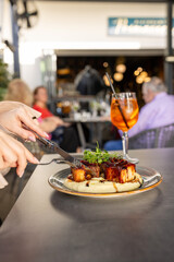 Close-up of female hands holding a knife and fork cutting meat on a plate