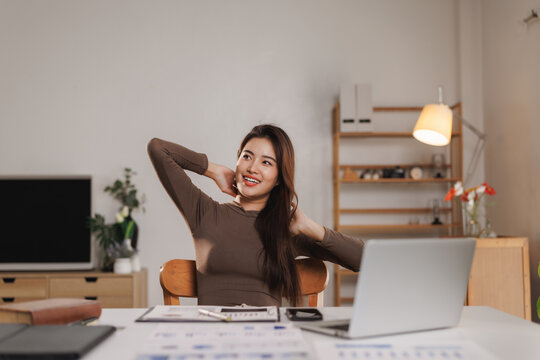 Asian freelancer relaxing at home office desk after work