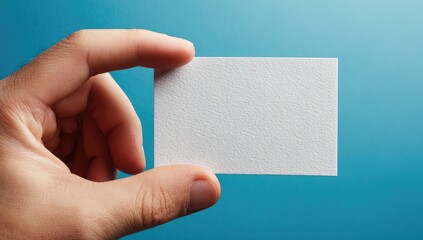 Hand holding blank white business card against a vibrant blue background