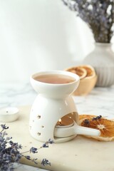 Aroma lamp with burning candle, lavender and dry orange slices on white table, closeup