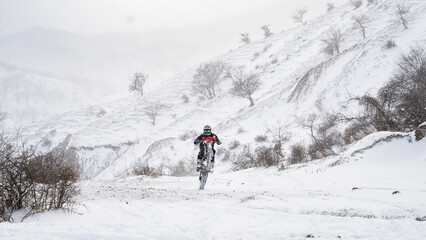 Enduro rider riding mountain motorcycle on snowy trail in winter landscape outdoors © Соня Монштейн
