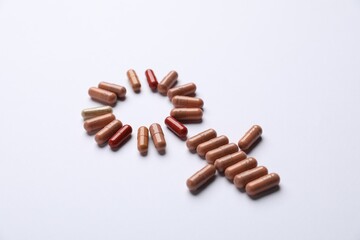 Menopause. Female gender symbol made with pills on light background, closeup