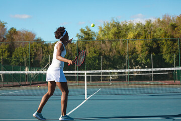 African American woman tennis player playing on hardcourt swinging racket chasing serve near net