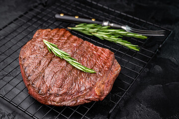A mouthwatering grilled top sirloin or rump beef steak, showcasing beautiful grill marks. black background. top view