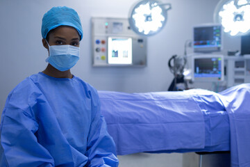 African American female surgeon adjusting light in operating room above operating table, copy space