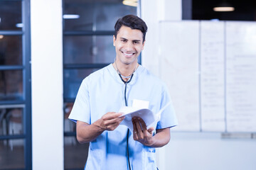 Stethoscope resting on patient charts leaning on whiteboard with glass partitions revealing desk