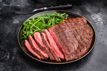 Juicy grilled top sirloin on a plate, accompanied by seasonal greens for a delicious meal. black background. top view