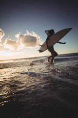 Naklejka premium Long white surfboard leaning against gentle waves as warm sunset light sparkling on wet sand