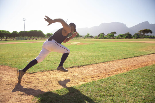 Male athlete sprinting along basepath on baseball diamond past grass and light poles, copy space