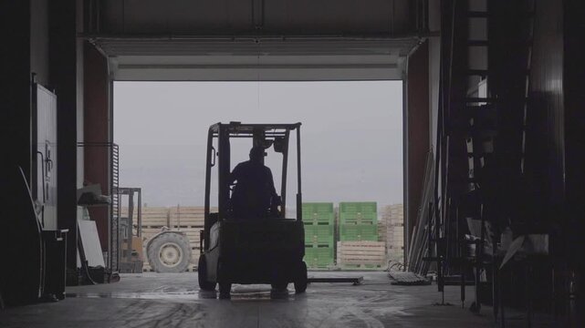 Forklift moves large wooden crates filled with fresh apples at an agricultural cold storage facility. Massive stacks of crates indicate fruit harvest logistics and post-harvest handling operations. - Powered by Adobe