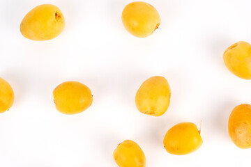 A scattering of bright yellow dates is placed randomly across a white background.