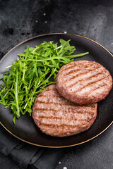 Grilled beef and pork meat patty paired with fresh veggies, an essential component for gourmet burgers. black background. top view