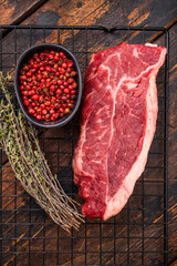 High quality raw striploin steak ready for seasoning, perfect for crafting the ultimate steak dinner experience. wooden background. top view