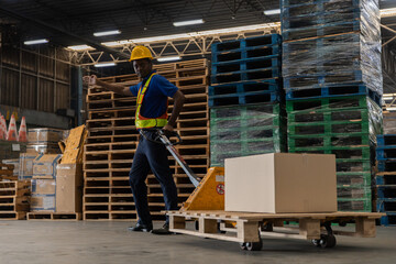 Warehouse worker in safety gear using a pallet jack to move cardboard boxes inside a distribution center. Industrial logistics concept showing manual handling in supply chain operations.