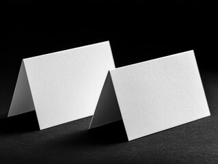 Two blank, white, folded place cards on black background