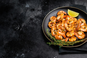 Grilled spicy Shrimps Prawns with garlic and lime in a plate. Black background. Top view