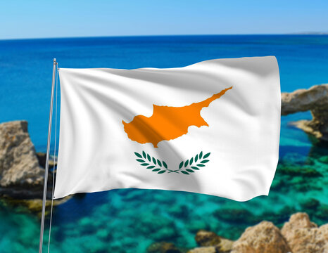 Waving Cyprus national flag on flagpole with Mediterranean Sea and rocky coast background. Represents culture, heritage, patriotism, tourism, history, and national identity of the Republic of Cyprus - Powered by Adobe