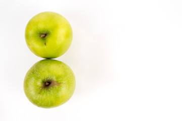 A top down shot shows two green apples placed in a vertical stack on a white background.