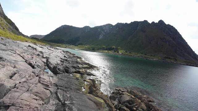 Rocky coastline of Rorvik, in Lofoten, Norway from FPV done, flying low over rocks and surf.
