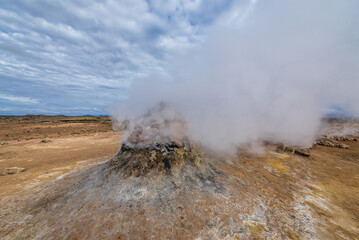 Steaming cone in Hverir geothermal area with boiling mudpools and steaming fumaroles in Iceland