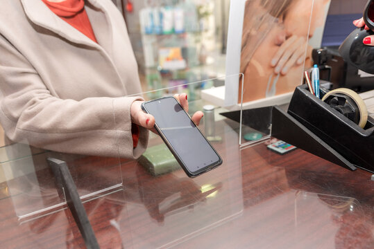 Close up of Customer showing smartphone screen with prescription to pharmacist in a pharmacy - Powered by Adobe