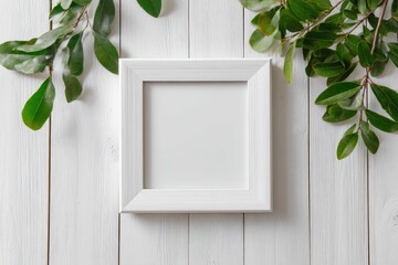 White square frame on white wooden background, surrounded by green leaves