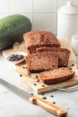 Chocolate zucchini bread cake sliced. Moist chocolate cake with grated zucchini, cocoa powder and chocolate chips on white tile kitchen background