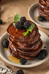 Chocolate Pancakes close up. Pancakes with honey glaze and blackberry on top brown table background. Homemade classic american pancakes