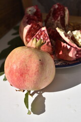 Whole pomegranate next to open pomegranate on plate