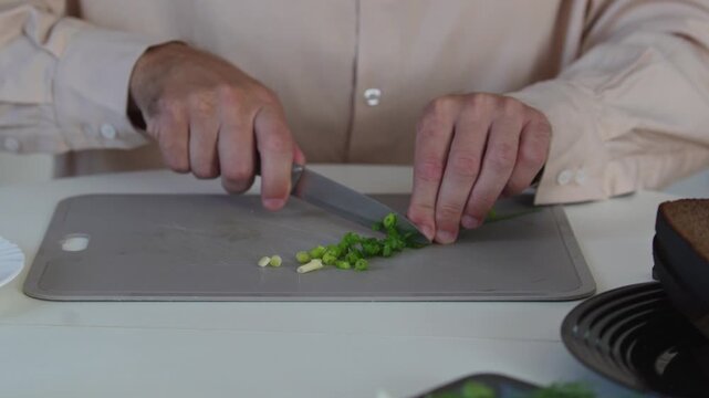 A chef professionally prepares a fresh vegetable salad, chopping potatoes, eggs, and greens. Dynamic cooking process showcasing culinary skills and healthy food preparation