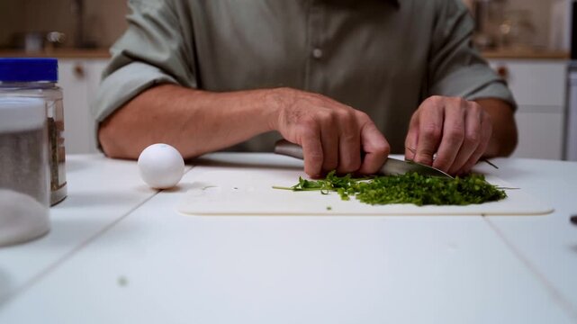 A chef professionally prepares a fresh vegetable salad, chopping potatoes, eggs, and greens. Dynamic cooking process showcasing culinary skills and healthy food preparation